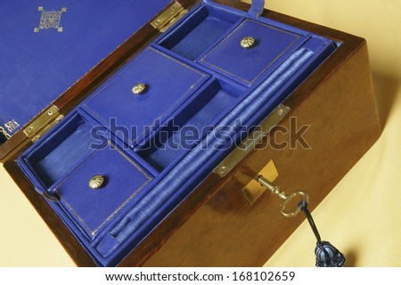 An open old jewelry box with compartments on blue velvet