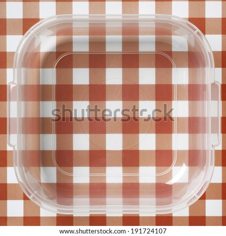 Plastic packaging over a red and white tablecloths. Square format
