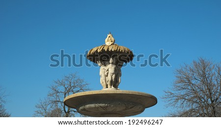 Stone fountain in a park with blue sky. Horizontal