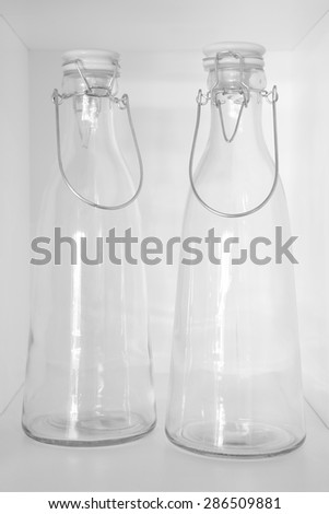 Empty crystal bottles in a cupboard with white background. Vertical