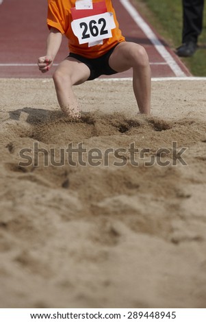 Female long jump competition with woman falling in the sand. Vertical