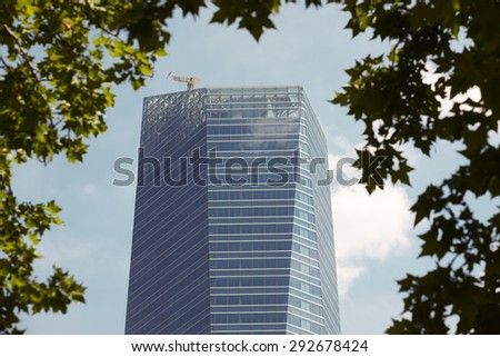 Modern building metallic and glass facade detail with tree limb. Horizontal