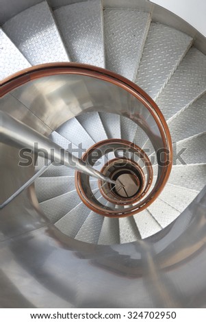 Metallic spiral stair with wooden handrails inside a lighthouse. Vertical