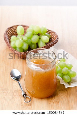 grape jelly jar on the board with grapes in a basket in the background
