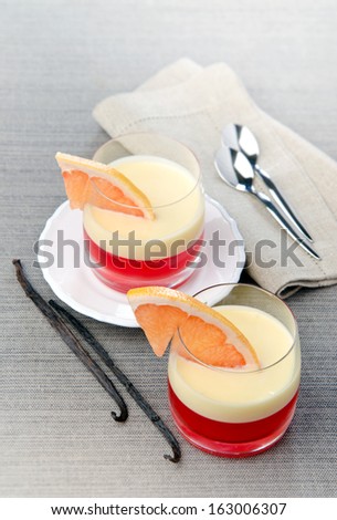 dessert of mascarpone cheese and jelly with grapefruit, vanilla in glass cups with spoons and a napkin in the background