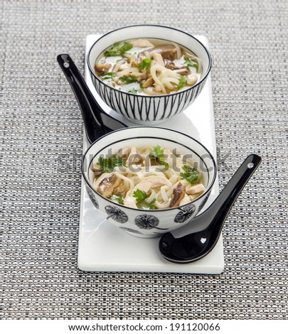 Thai soup in ceramic bowl of ceramic spoons on a gray background