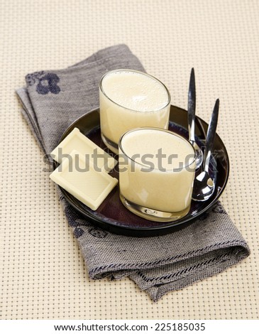 White chocolate mousse in glass cups on a plate with chocolate chips