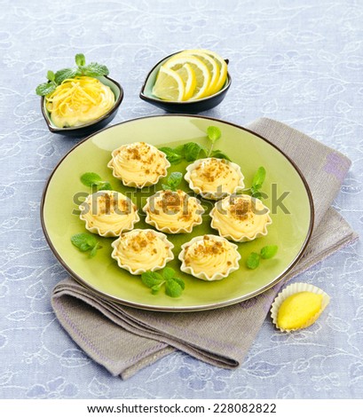 Tartlets with lemon cream with mint leaves on a green plate
