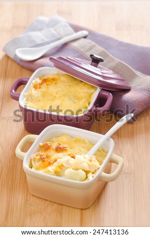 cauliflower gratin with cheese in ceramic cocotte on the board of bamboo