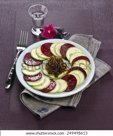 beet carpaccio vegetables zucchini with onions jam on a plate of blue color on a lilac background