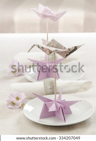 The decor for the wedding table Origami Crane on a plate with sakura flowers near the napkin rings of Bisser
