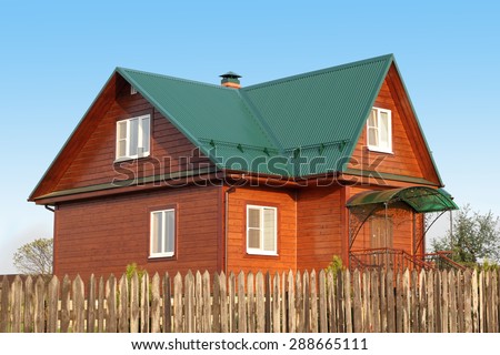 Wooden house under green metal roof with white plastic windows with jalousie photo