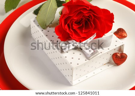Romantic dinner setting with a rose and gift box