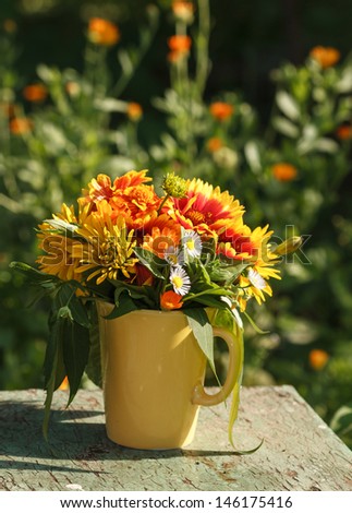 Bouquet of summer flowers in a yellow mug