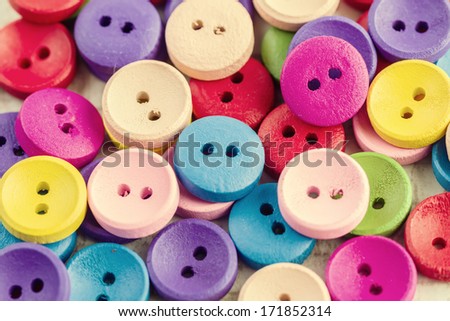 Lots of colorful buttons for clothes on wooden background