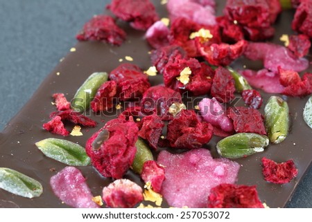 Dark chocolate bar with berry fruits, rose petals, pistachios and gold powder