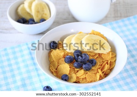 Breakfast cereal with blueberries, bananas and milk on a rustic wood table