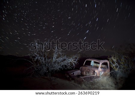 Abandoned vintage auto in the desert, under star trails, Joshua Tree National Park