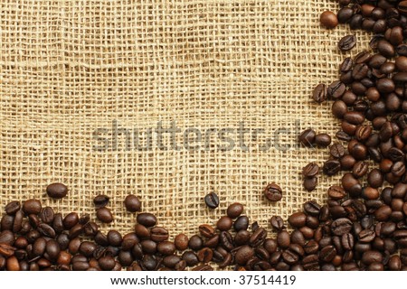 Textured background of coffee beans and sandy brown burlap cloth
