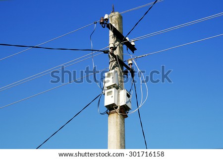 The post power lines with power line cables and electricity meters against the blue sky