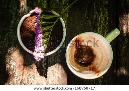Cup of hot chocolate milk with beautiful flower and coffee ground on vintage wooden background, selective focus