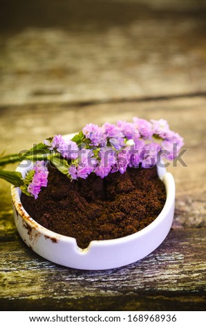 Beautiful flower and coffee ground on vintage wooden background, selective focus