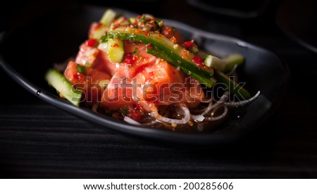 Salmon salad on black plate and black background. Selective focus, shallow depth
