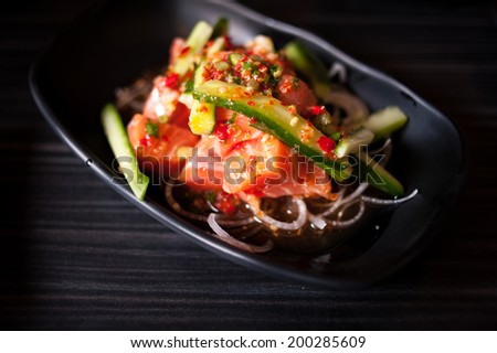 Salmon salad on black plate and black background. Selective focus, shallow depth