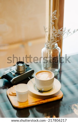 A cup of latte coffee with cracker in warm tone light coffee cafe\'