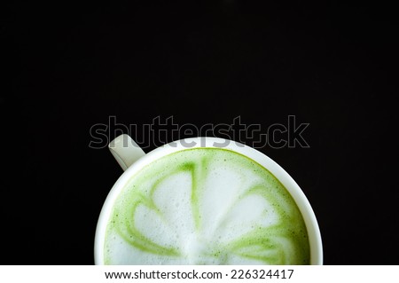 Hot milk green tea (selective focus) in the white cup on the dark wooden table.