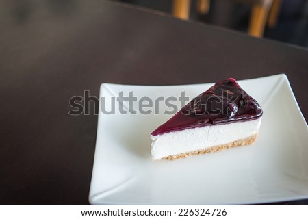 blueberry cheesecake (selective focus) in the white plate on the dark wooden table.