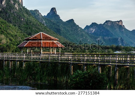 Wooden Bridge in Lotus Lake Under Cloudy Sky at Khao Sam Roi Yod National Park, Thailand.