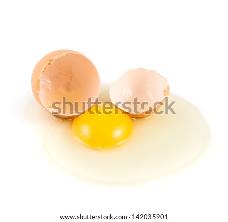 Cracked and broken into two halves egg shell with the spilled yolk and protein over the white background