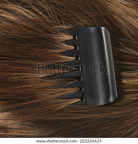 Straight hair fragment with the black comb as a texture background composition