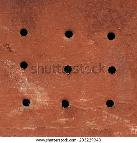 Red painted grungy metal surface with holes as an abstract background composition