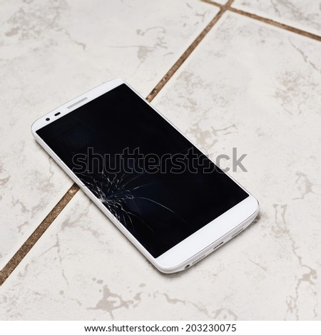 Smart phone with the broken screen over the ceramic floor tiles