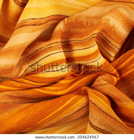 Fragment of a wrinkled striped orange and yellow colored fabric cloth as a background texture