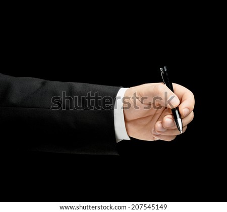 Caucasian male hand in a business suit, holding the pen, low-key lighting composition, isolated over the black background