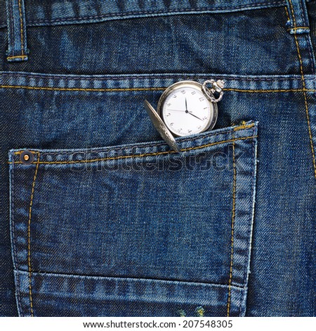 Old metal pocket watch in a back pocket of a navy blue denim jeans as a background composition