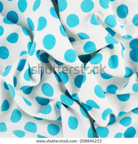 Fragment of a white and blue wrinkled polka dot cloth fabric as a background texture