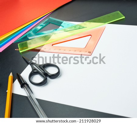 Black desk\'s surface covered with multiple stationery office supplies as a background back to school composition