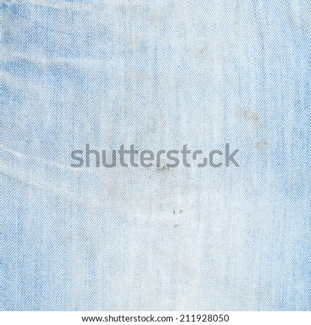Wrinkled jeans denim stained light blue cloth fragment as a background texture composition