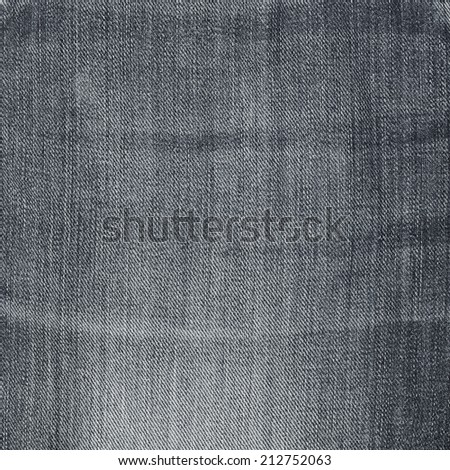 Wrinkled dark gray jeans denim cloth fragment as a background texture composition