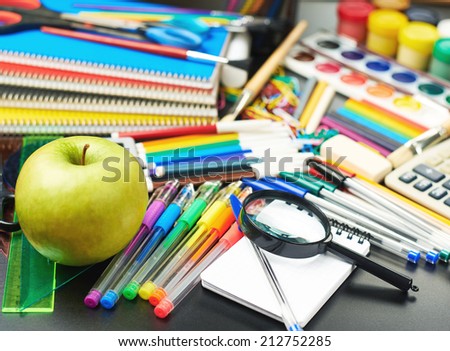 Black desk\'s surface covered with multiple stationery office supplies as a background back to school composition