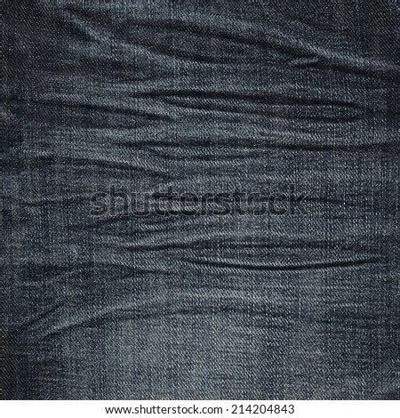 Wrinkled black jeans denim cloth fragment as a background texture composition