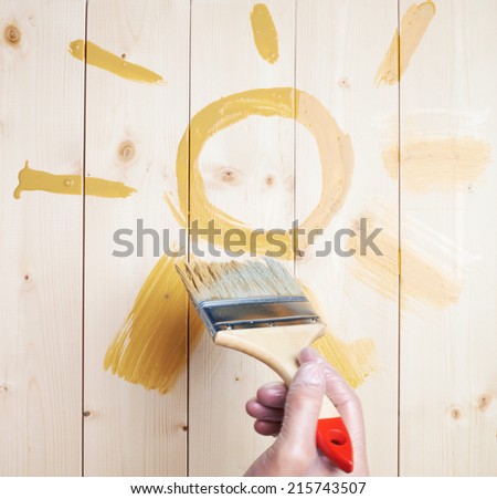 Drawn symbolic yellow sun drawn with the wide brush over the polished wood boards