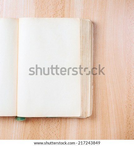 Composition of the opened old book with the empty pages over the wooden table