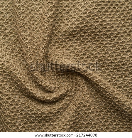 Creased knitted beige cloth material fragment as a background texture composition