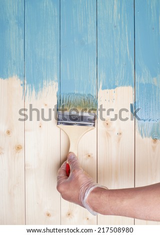 Process of painting the pine wood boards with the brush and the blue paint