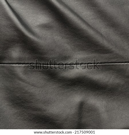 Creased black leather material fragment as a background texture composition